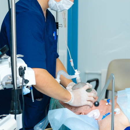The doctor applies an oxygen mask to the face of an elderly man. Preparing a patient for surgery in a hospital operating room.の写真素材