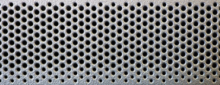 Grid in the form of round holes in a silvery plastic panel. Perforated surface with mesh pattern. Abstract background.の写真素材