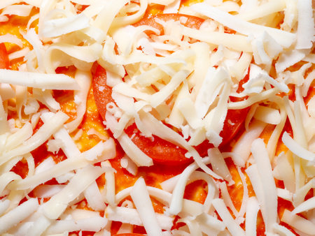 Cheese sticks and raw tomatoes on a pizza base close-up. Pizza Margherita assembled and prepared for baking in the oven.の写真素材