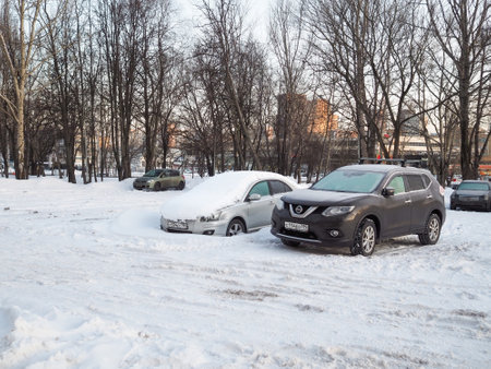 Moscow. Russia. February 28, 2023. Snow-covered cars in a snow-covered city parking lot on a winter morning.のeditorial素材