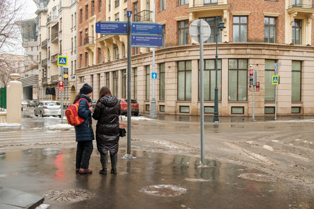 Moscow. Russia. February 25, 2023. Two women from the back at the crossroads of empty streets in the city on a winter day.のeditorial素材