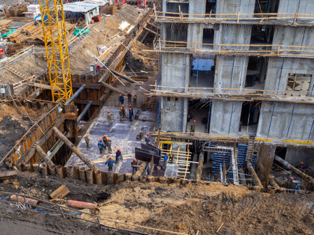 Moscow. Russia. April 1, 2023. Lots of builders in orange helmets and uniforms at the construction site. Top view of the construction of a concrete monolithic building.のeditorial素材