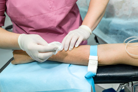 The doctor disinfects the patient's hand with an alcohol solution. Preparation for the installation of a catheter dropper for intravenous infusion of drugs.の写真素材