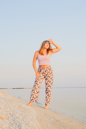 Happy young attractive female traveler in enjoys vacation on the sea beach. A young girl basks in the sun on the seashore. Krasnodar region. Russia. August 28, 2023.のeditorial素材