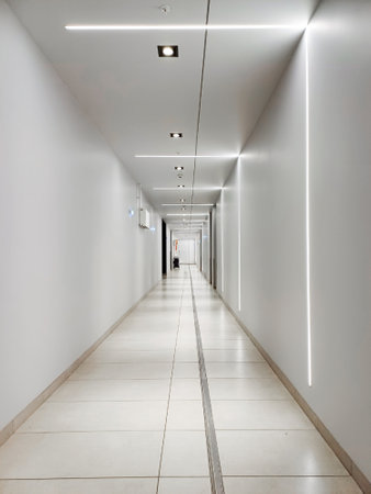 Long white tunnel with LED lighting. Empty white walls and corridor in a modern building.の写真素材