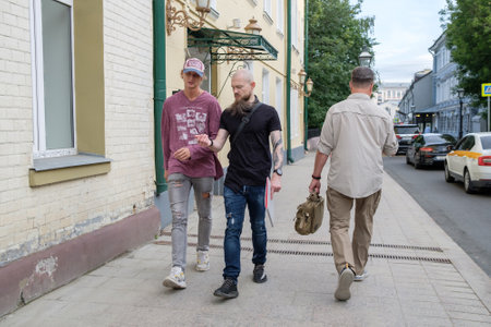 Male pedestrians walk along a city street on a summer day. A bearded man walks along the sidewalk. Moscow. Russia. July 2, 2024のeditorial素材