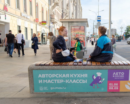 Young women sit on a bench on a city street on a summer day. Moscow. Russia. June 30, 2024.のeditorial素材