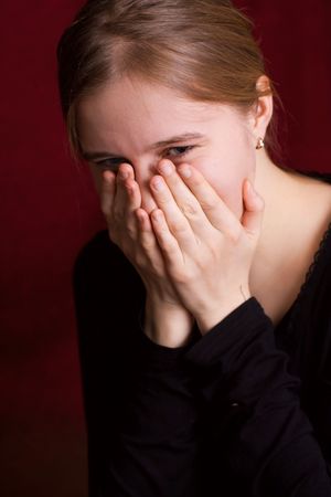 beautiful crying girl on dark red backgroundの写真素材