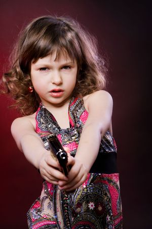 portrait of little girl with pistol on blackの写真素材