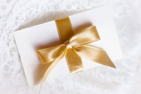 letter with golden ribbon on white laceの写真素材