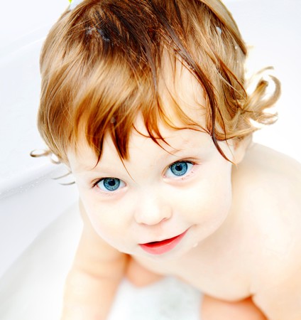 adorable blue-eyed baby taking a bathの写真素材