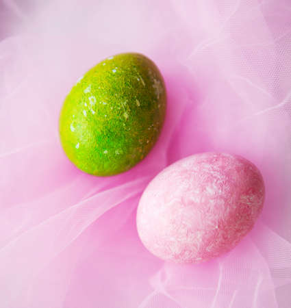 pink egg and green egg on pink textile background