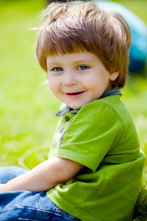 portrait of cute little boy sitting on the grassの写真素材