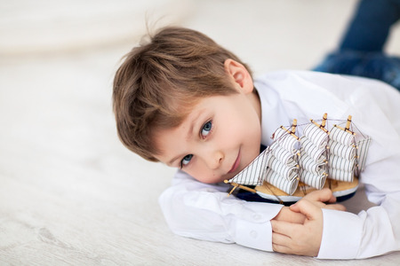Portrait of cute little boy with ship in his handsの写真素材