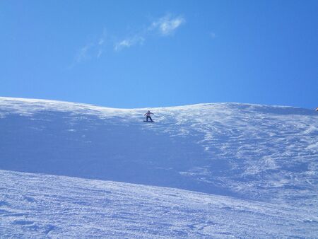 A snowboarder alone on a mountain slopeの写真素材