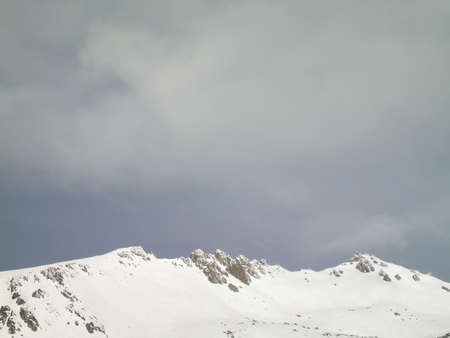 Storm clouds over a snowy mountain topの写真素材