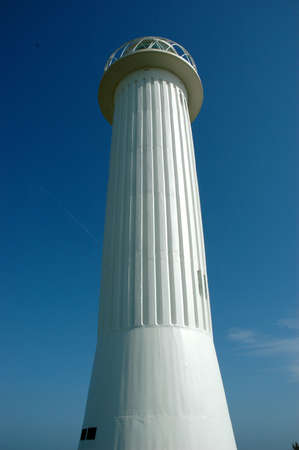 A white lighthouse against a blue skyの写真素材