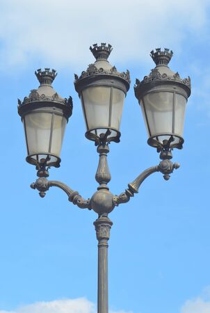 A grey Parisian lamp post against a blue skyの写真素材