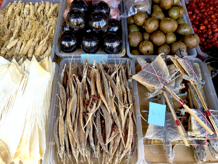 A range of foods for sale in a Vietnamese market. These include dried seahorse, dried lizards, and colourful vegetables and roots.の写真素材