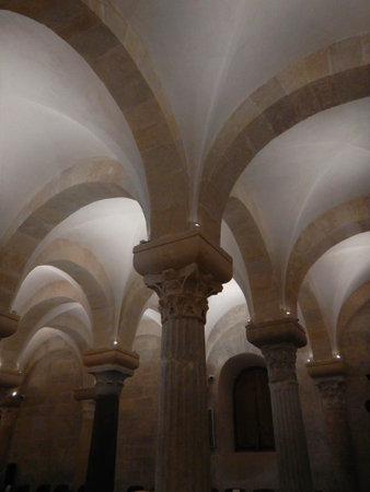 Multiple arches form a vaulted ceiling of an old crypt. Large stone blocks form the walls and arches. The pillars are mismatched.の写真素材