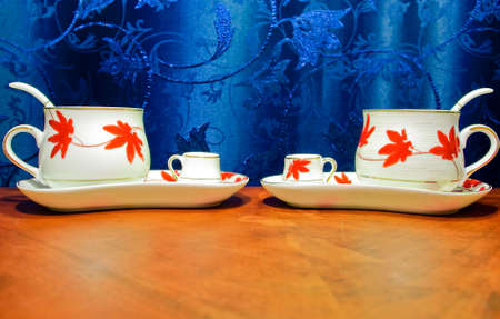 Cups with coffee and spoons inside, small caps with cream on saucer