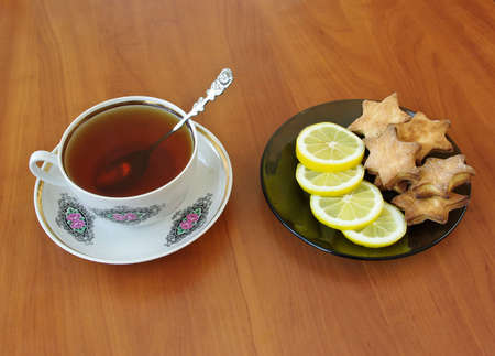 Teacup and homemade cookies with slices of lemon on plateの写真素材