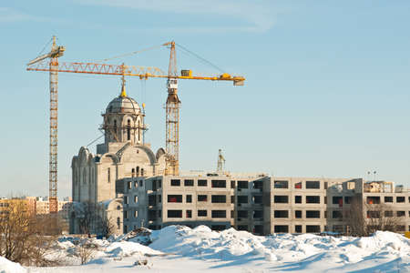 Apartment house and church construction with cranes in winterの写真素材