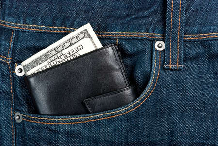 Black leather wallet with dollars in jeans pocketの写真素材