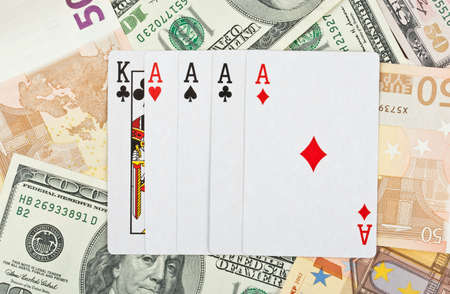 Playing cards on heap of euro and dollar banknotesの写真素材