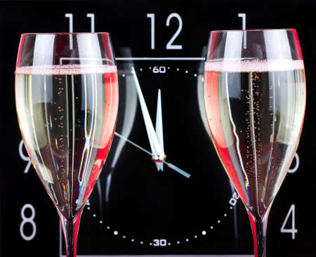 Champagne flutes with clock on background showing 3 minutes before New Year
