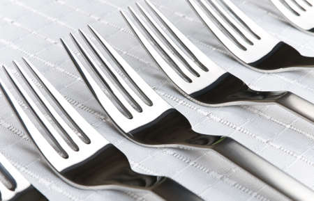 Row of silver forks over white tableclothの写真素材