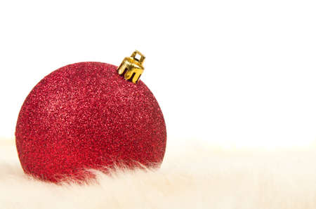 Red christmas ball on fur isolated on whiteの写真素材