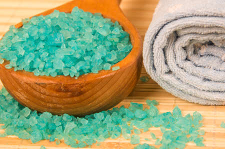 Blue bath salt in spoon and rolled towelの写真素材