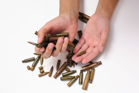 Bullets, cartridges in children's hands In children's pockets on a white background bullets and cartridges of war. Isolatedの写真素材