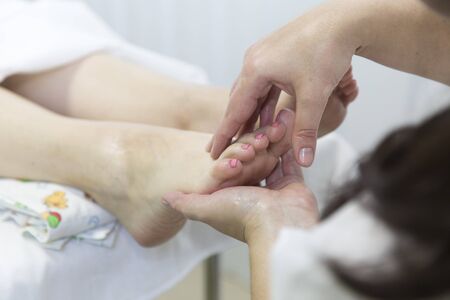 Foot massage. Foot massage in the patient. The doctor does the massage of the feet, heels and toes on the legsの写真素材