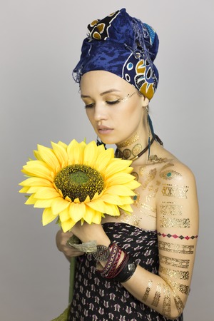 Girl with sunflower. Model woman in African style clothes with a sunflower in hands on a photo sessionの写真素材