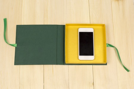 Phone as a gift on the light wood. Mobile phone in a gift box against a of light wood boardsの写真素材