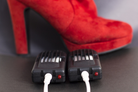 Electric dryer for shoes. Red women's boots are dried using an electric dryer device.の写真素材