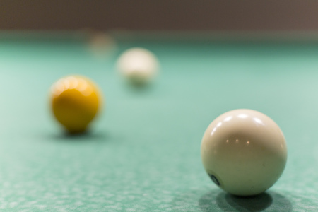 On the green table cloth three balls roll.