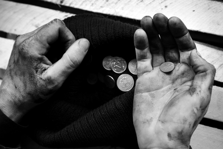The beggar considers coins. A beggar on the street is holding dirty hands with moneyの写真素材