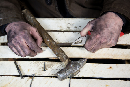 Dirty hands of workers with tools hammers and nails. Heavy low-paid work for little money.