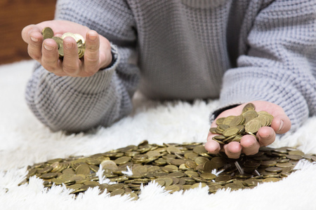 The man is holding coins. An elderly man pour metal money on his hands and on the floor.の写真素材