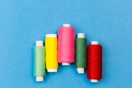 Coils with multi-colored threads on a blue background. Threads for sewing different colors are...