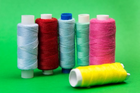 Threads of different colors on a green background. A few coils with bright multicolored threads...