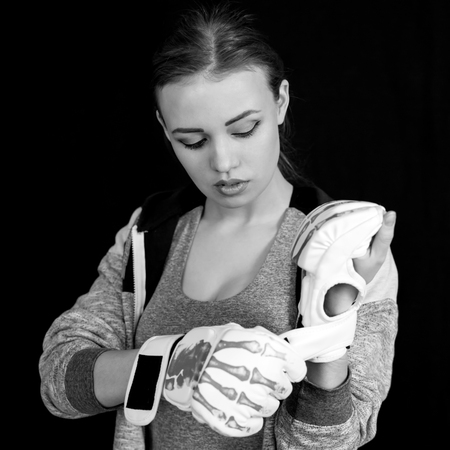 Girl sportswoman in gloves for boxing on a black background. The girl is a fighter of mixed martial arts who covers her face with gloves from blows.の写真素材