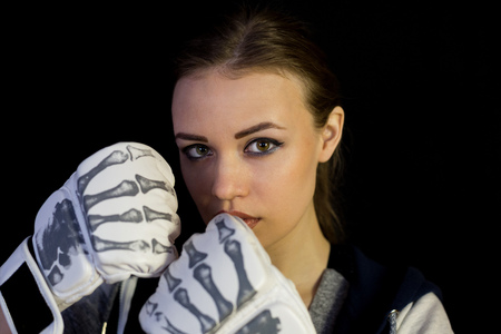 Girl sportswoman in gloves for boxing on a black background. The girl is a fighter of mixed martial arts who covers her face with gloves from blows.の写真素材
