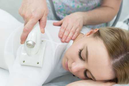 LPG massage of hands and shoulders. A beautiful blonde in a beauty salon.の写真素材