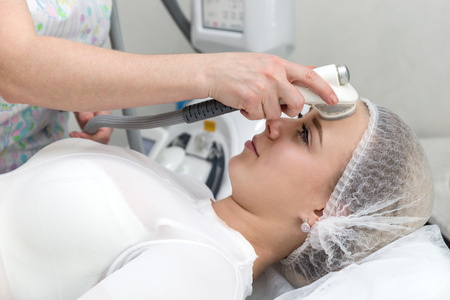 Removing wrinkles on the face and neck with massage. A beautiful blonde smooths wrinkles on the face and neck area with the help of LPG.の写真素材