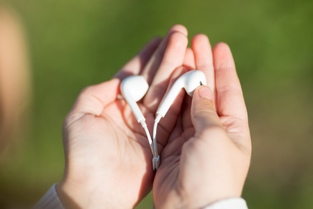 Audio headphones in children's hands. In the palms of the hands are headphones from a mobile phone.の写真素材
