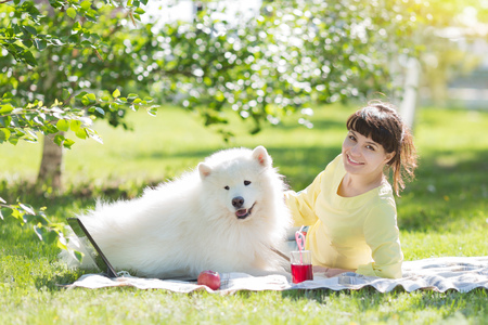 A brunette girl with a white dog on nature.の写真素材